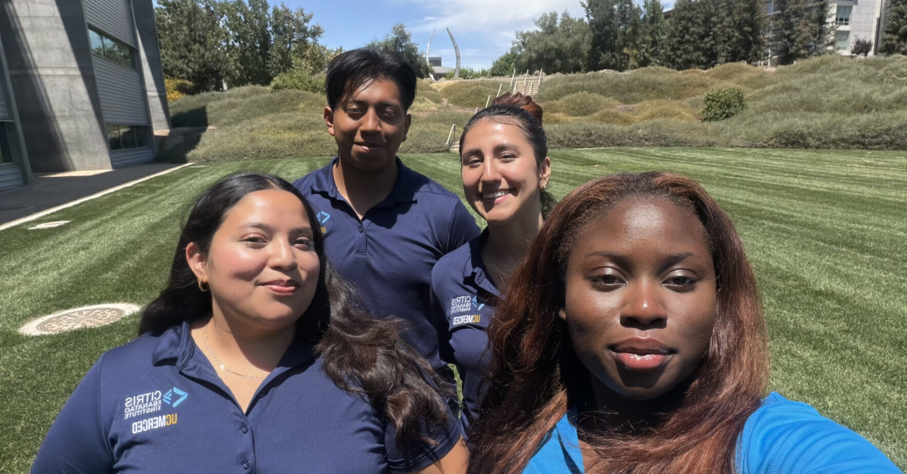 Photo of a group of four CITRIS interns standing on a grass field