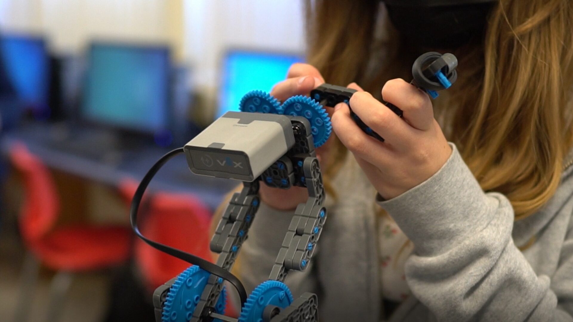 Student (face hidden) working with VEX educational robot